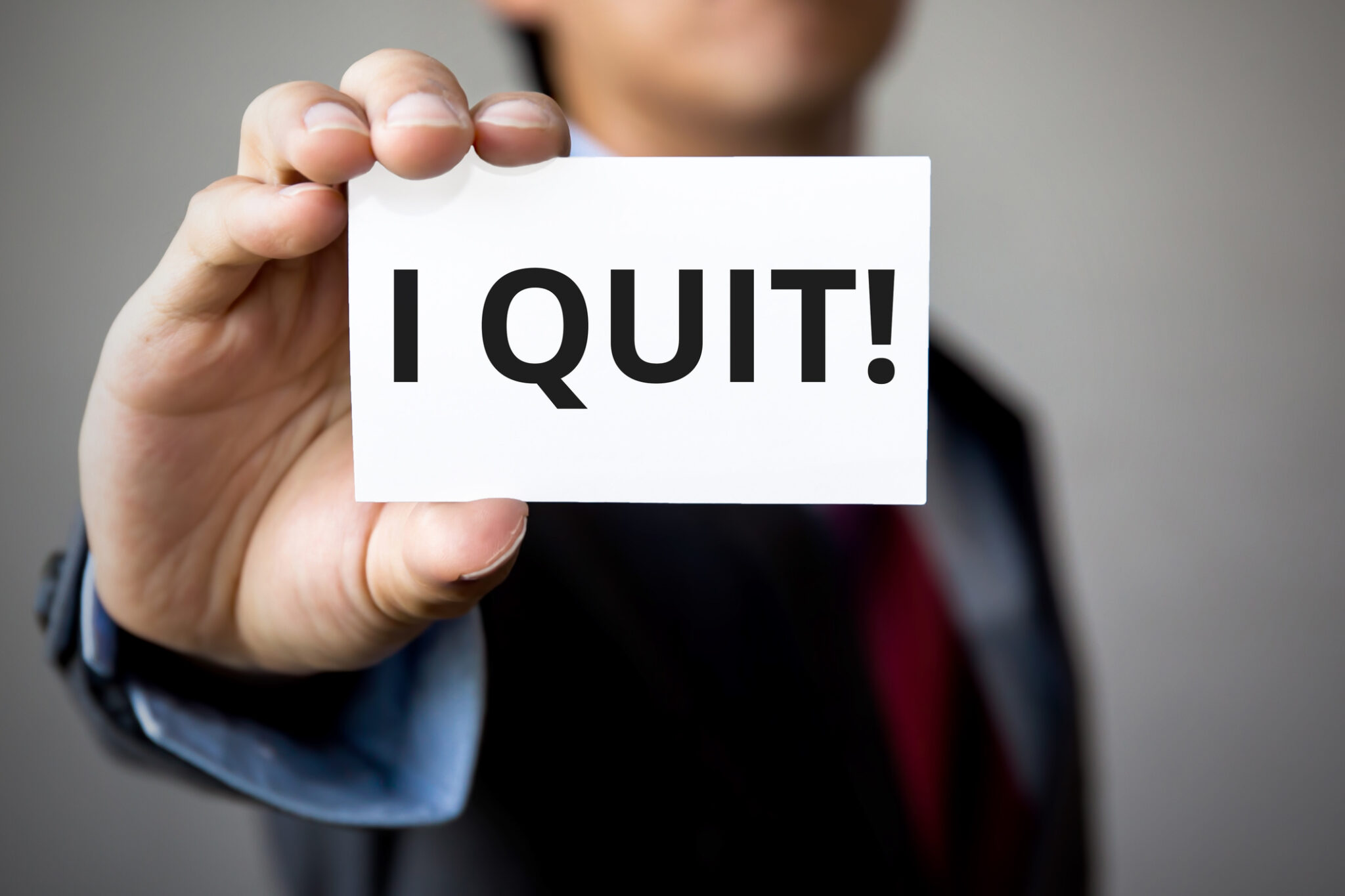 Businessman presenting 'I Quit' word on white card